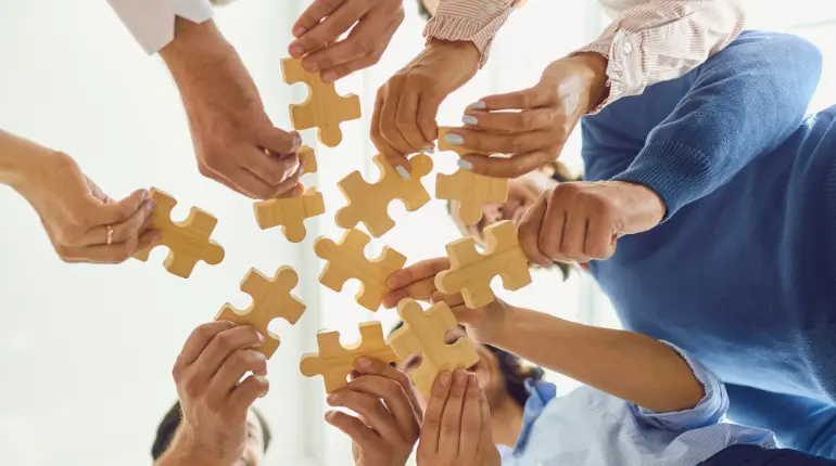 people holding large jigsaw puzzle pieces