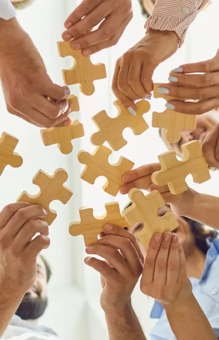 people holding large jigsaw puzzle pieces together